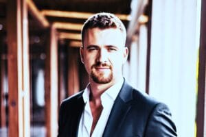 Benedikt Gruber im Business-Outfit lächelnd vor neutralem Hintergrund mit professioneller Körperhaltung