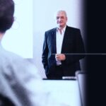 Finanzexperte auf dem Weg zur Eigenverantwortung und finanziellen Autarkie, Bücher und Laptop im Hintergrund