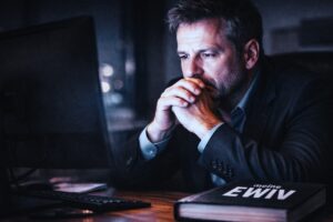 Ratloser Unternehmer nachts am Computer mit EWIV-Buch – Symbolbild für Ärger durch fehlerhafte Rechtsformwahl